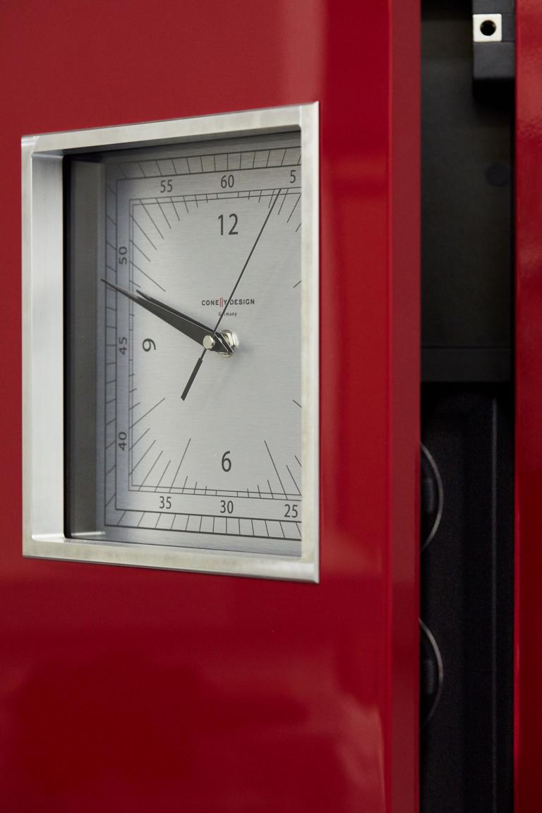 Eine elegante rote Uhr mit weißem Zifferblatt, weißem Außenrahmen und silbernen Zeigern