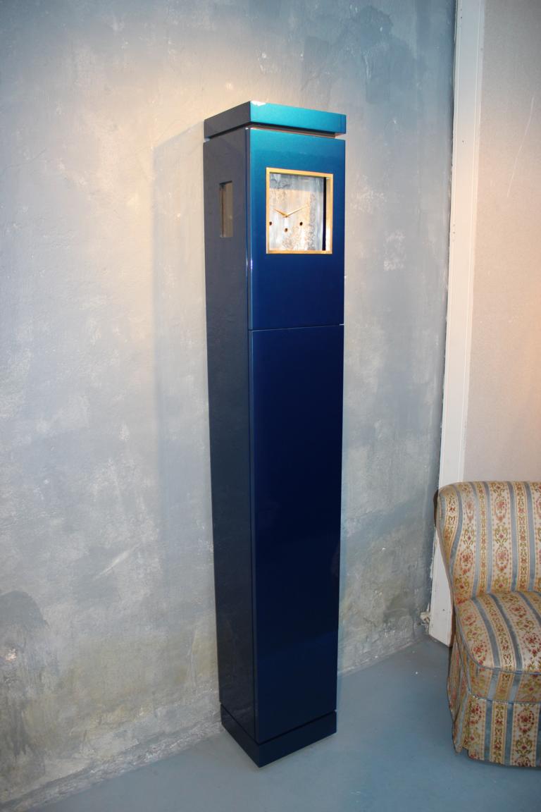 Eine hellblaue Standuhr vor einer grauen Wand mit einer geschlossenen Front als Versteck für wichtige Gegenstände